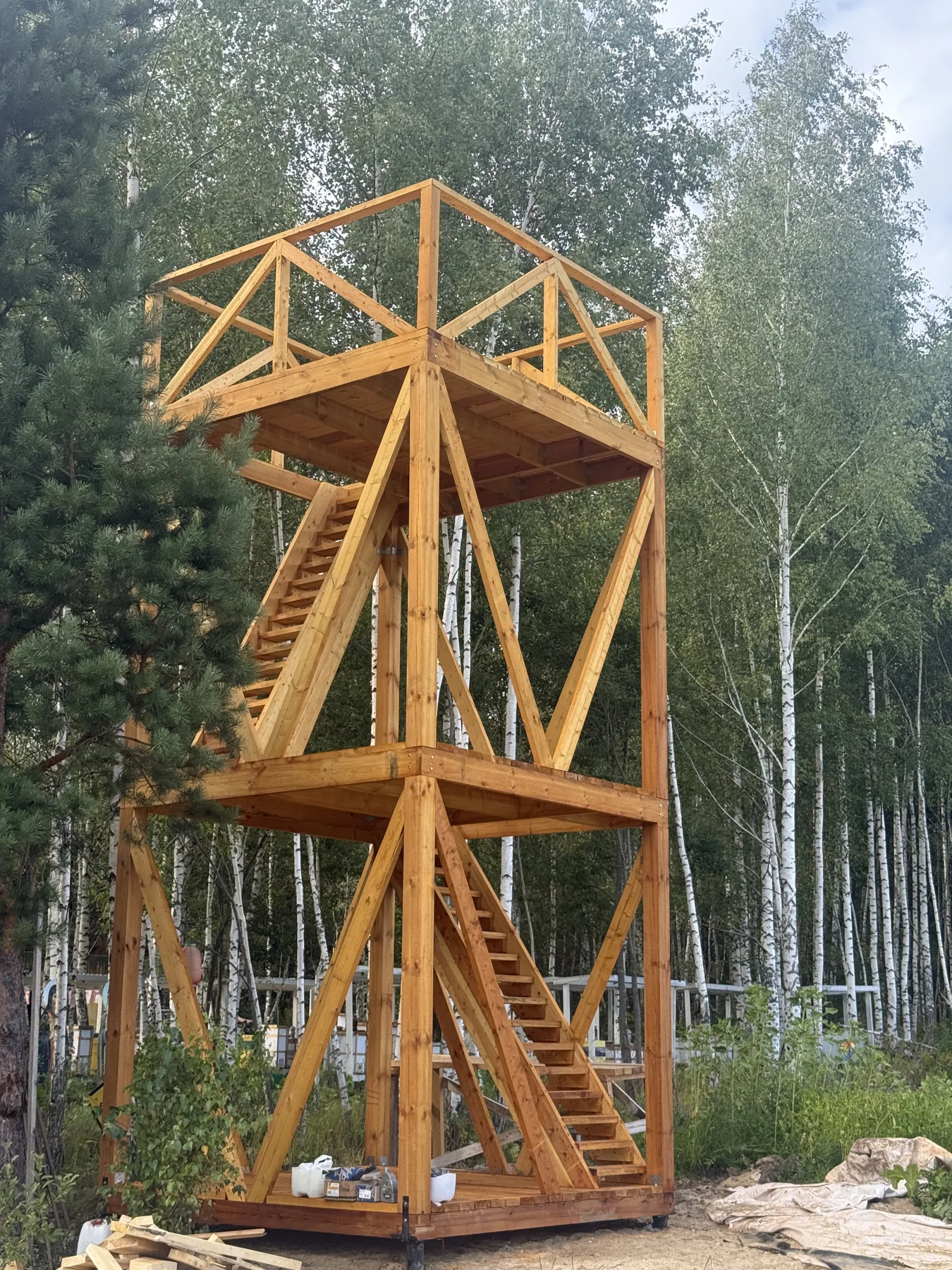 Деревянная башня с лестницей на фоне берёз